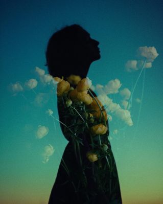 Enchanting double exposure of a woman's silhouette with yellow flowers against sky.